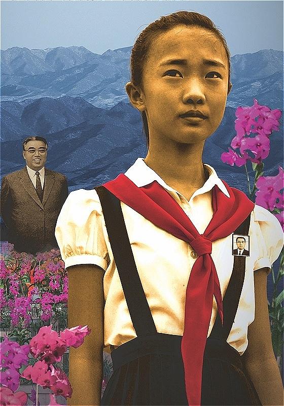 A close-up of a young girl amidst flowers and the mountains. A man stands in the background wearing a suit.