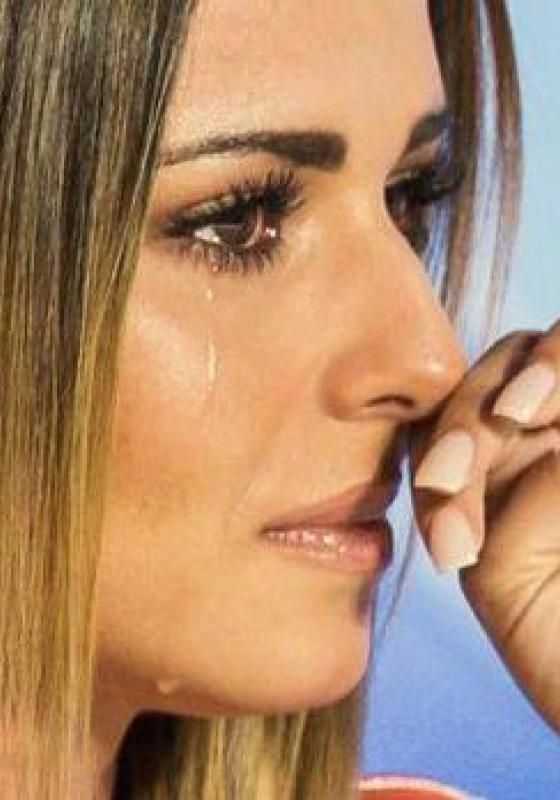 Side profile view of singer Cheryl Cole as a single tear runs down her face and she wipes her nose. 