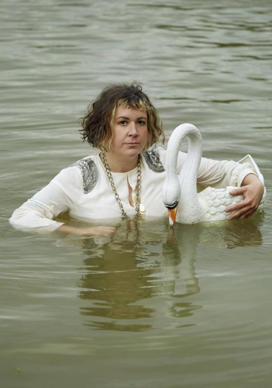 Amy stands in chest high water holding an ornamental toy swan.