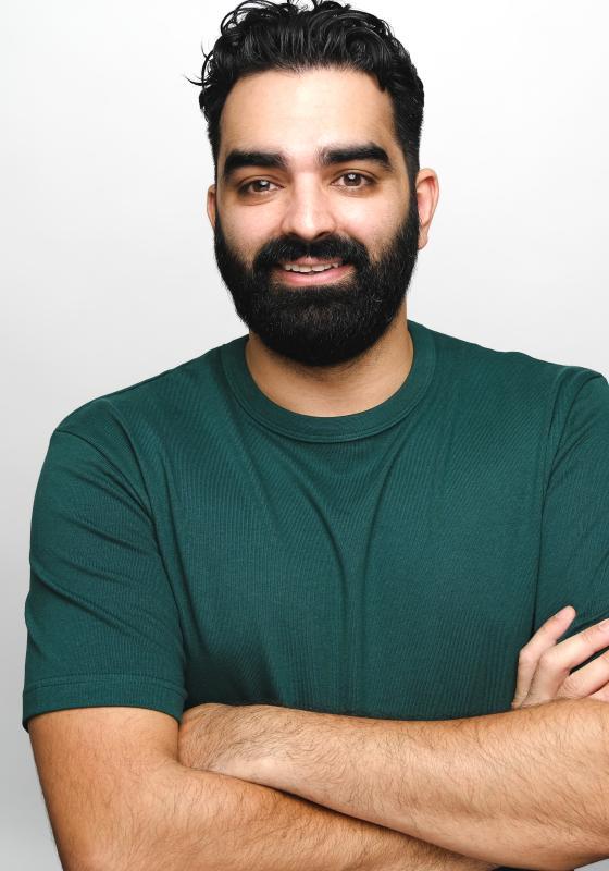 Peter stands with arms loosely folded wearing a dark green t-shirt.