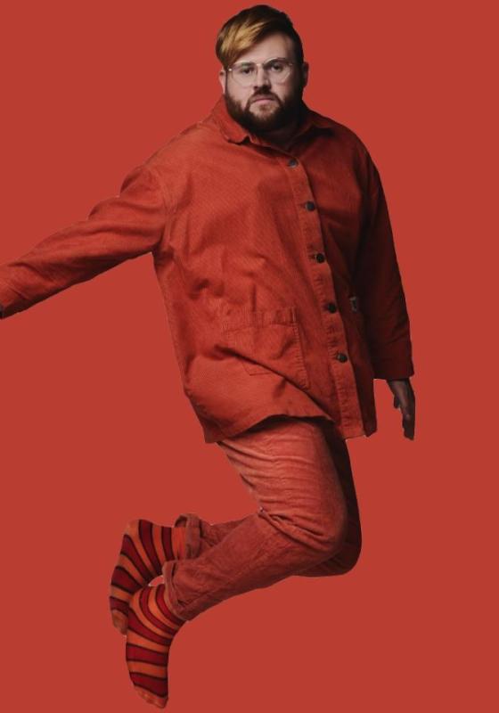 Ted Hill wearing all red jumping in the air with a solid red background