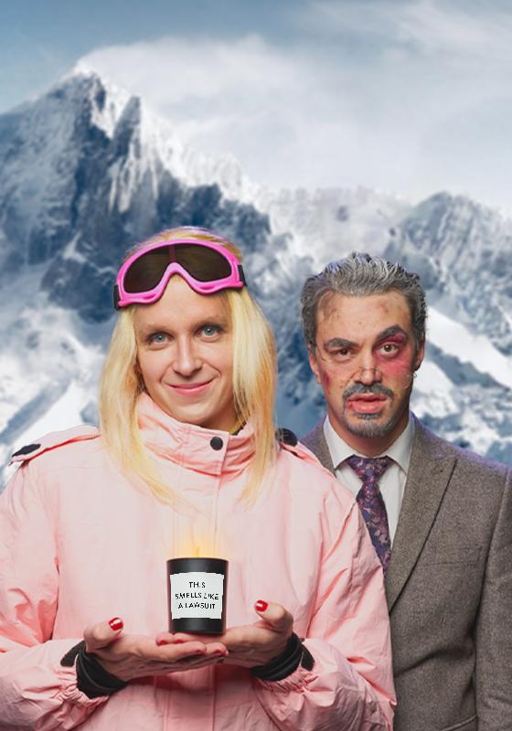 Linus dressed as Gwyneth looking pleased with herself in a pink ski coat wearing a blonde wig with big pink goggles resting atop of her head. She is holding a candle that says 'this smells like a lawsuit'. Joseph is placed just behind her looking dismayed at the camera with bruises across his face. The backdrop is of the ski alps.