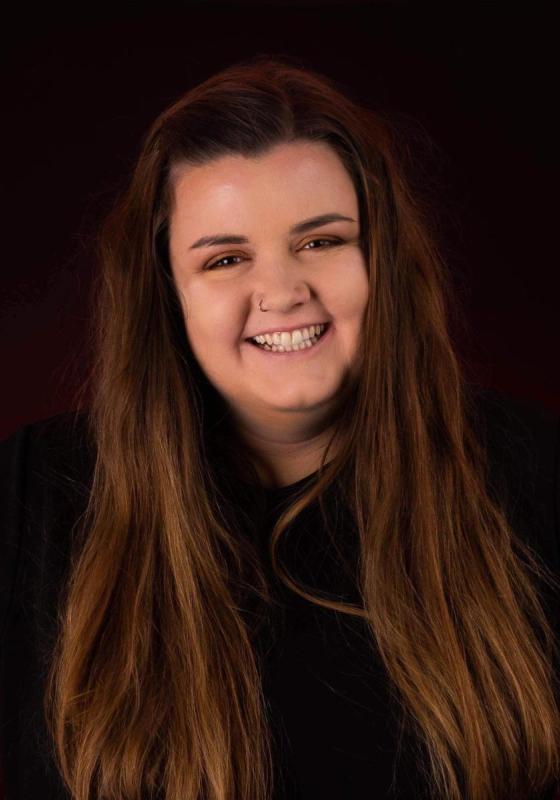 Headshot of Tal Davies against a dark background.