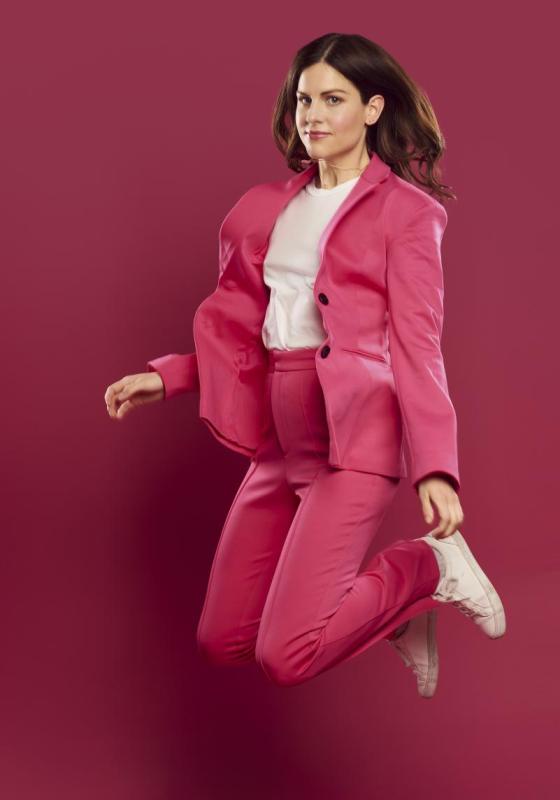 Micky wearing a hot pink suit jumping mid-air against a pink background