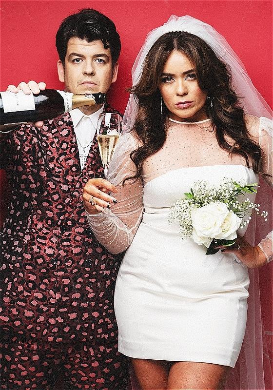 Laura & Joseph dressed as a bridge & groom pouring champagne.