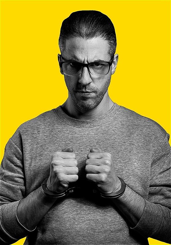 Grayscale picture of David in handcuffs, on a yellow background.