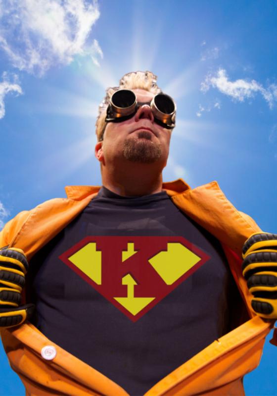 Doktor Kaboom with his trademark goggles and orange safetywear wearing a superman style K on his chest against a blue sky.