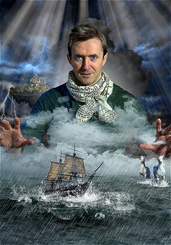 A performer is in the middle of a stormy sea wearing a white scarf and has their hands spread out in front of them.