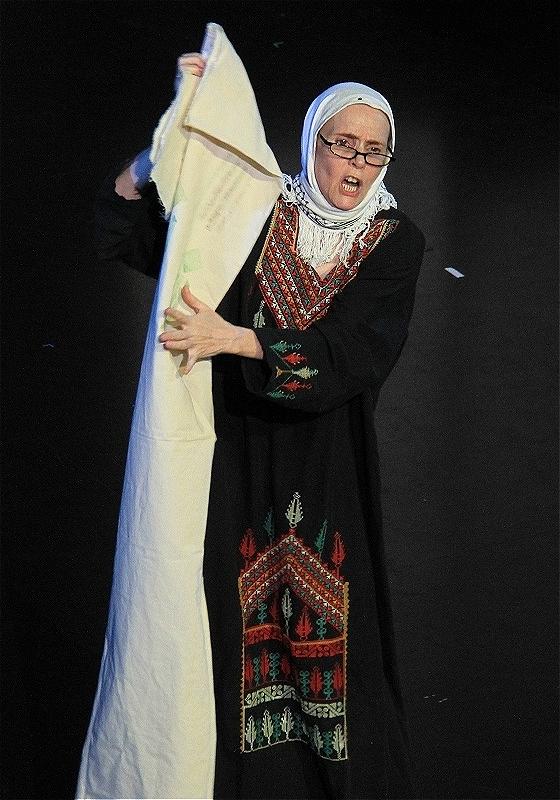 The performer is on stage, looking into the audience and holding a white piece of cloth.