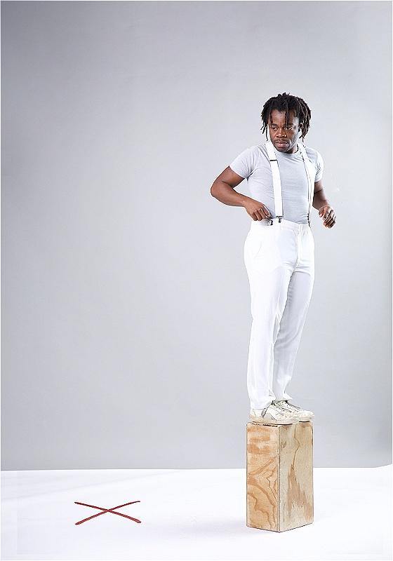 Demi standing on a wooden black with a spot on the floor behind him marked 'X'