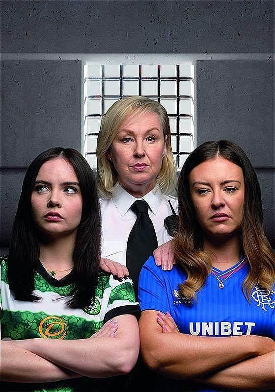 Two performers in football shirts with their arms crossed in front of a woman in a white shirt and black tie.