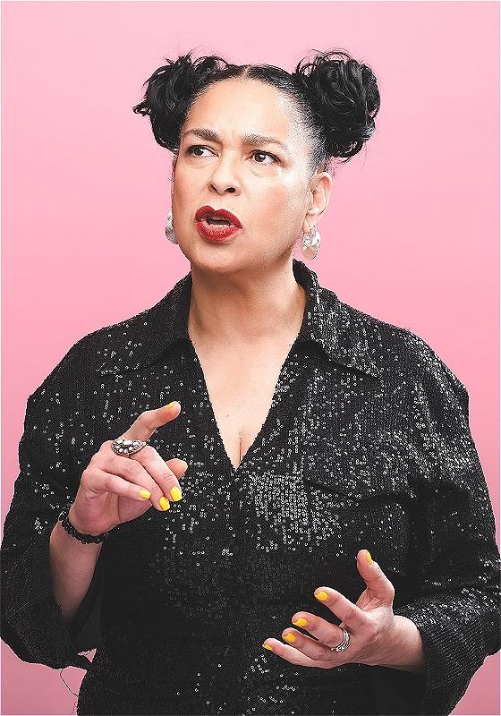 Josephine wears a sequined black top against a pale pink backdrop.