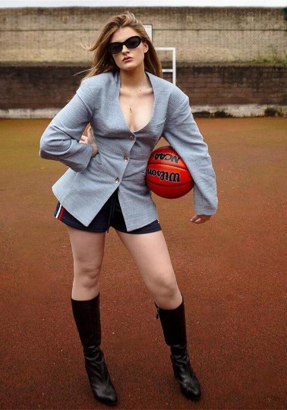 Freya stands with her hand on her hip holding a basketball under her arm.
