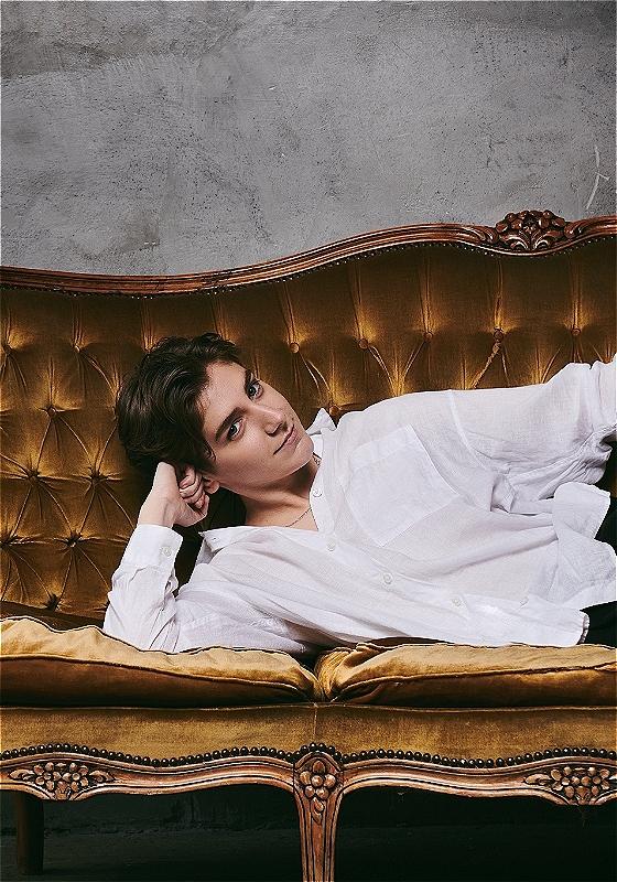 A person in a white shirt with their head on their arm lying on a couch