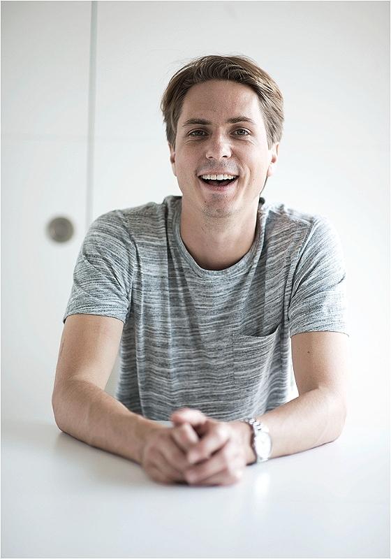 A man sitting at a table, wearing a smile on his face.