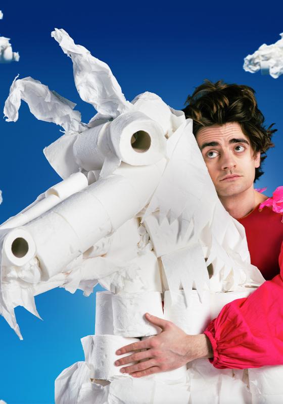 Luke cradles a unicorn made out of toilet paper with blue skies in the background.