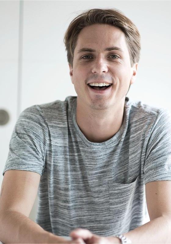 A man sitting at a table, wearing a smile on his face.