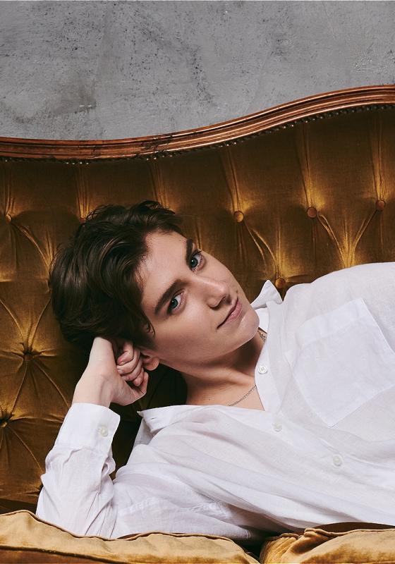 A person in a white shirt with their head on their arm lying on a couch