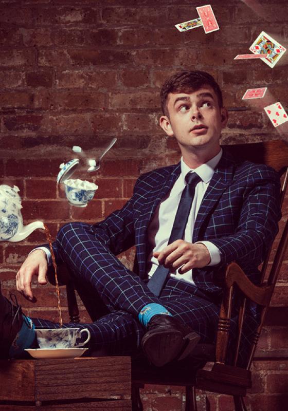 A person sitting in a chair with a teacup and teapot