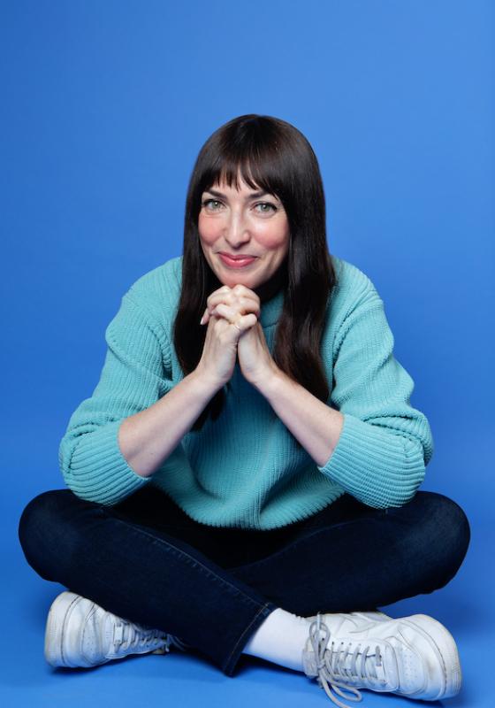 A person sitting cross legged with her hands folded together