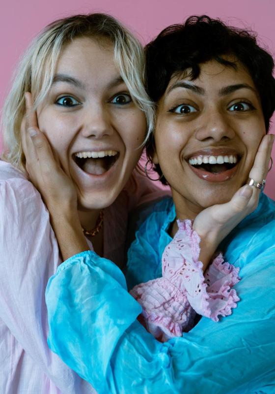 Two women smiling and holding their cheeks