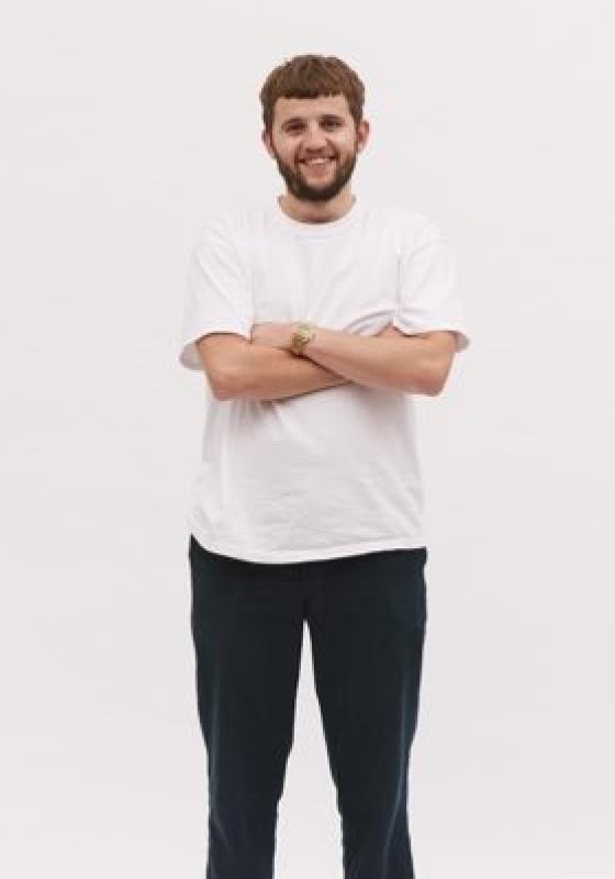 Rory smiling and standing with his arms crossed against a plain white background