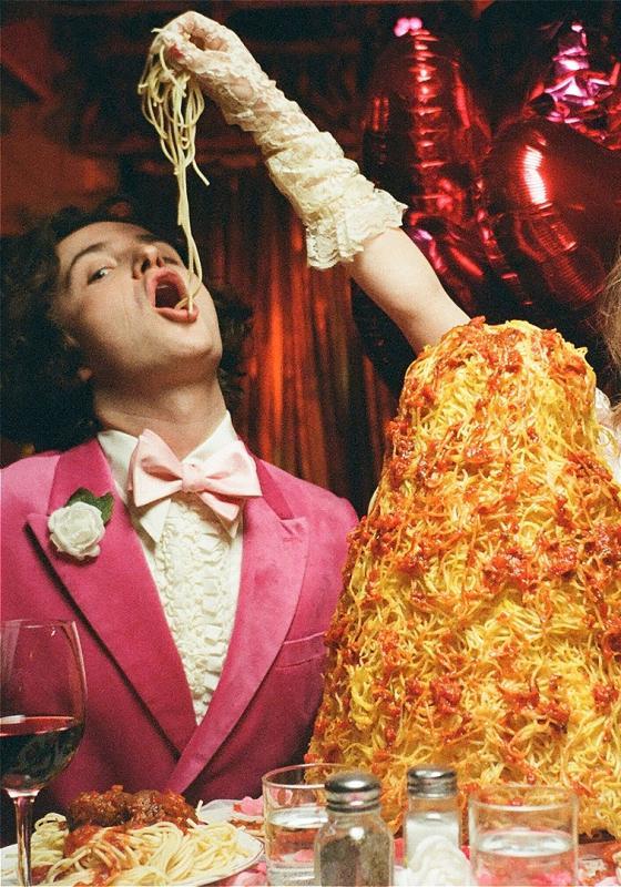 Imagine the biggest pile of spaghetti and meatballs you've ever seen. Now double it. This is the pile that sits on the table, as two people in pink eat it. 