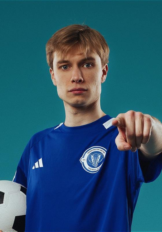 Ted in a blue football jersey, holding football, points at us.