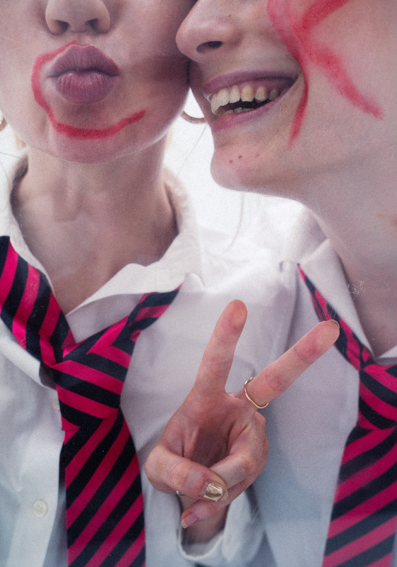 A closeup of two young girl's faces in school uniform. One has a C on their face and the other has a K in red pen.