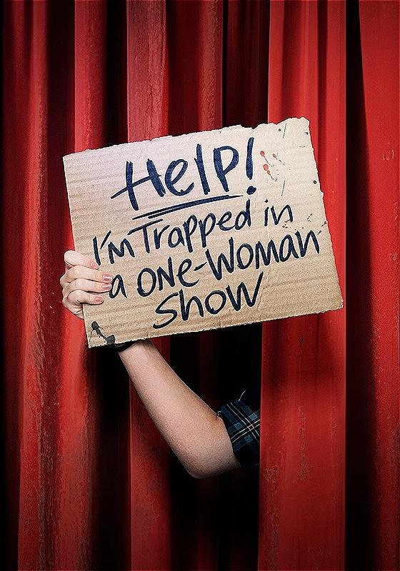 A hand appears holding a sign reading 'HELP! I'M TRAPPED IN A ONE WOMAN SHOW' from in between a red theatre curtain.