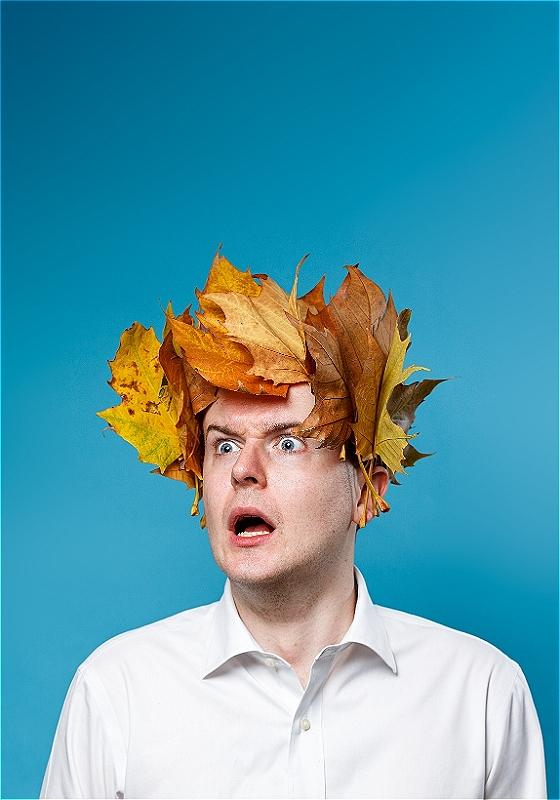 An anguished looking Andrew Doherty wears a laurel wreath made of leaves on their head, staring out at the viewer.