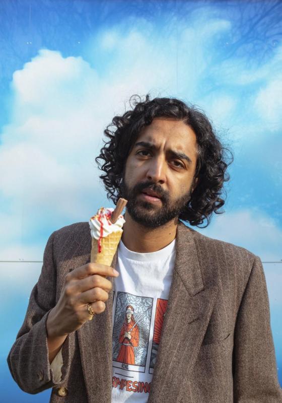 Rajiv looking pensive holding a ice cream cone against a bright blue sky