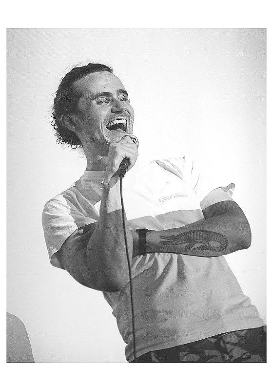 Black and white image of the comedian on stage mid laugh