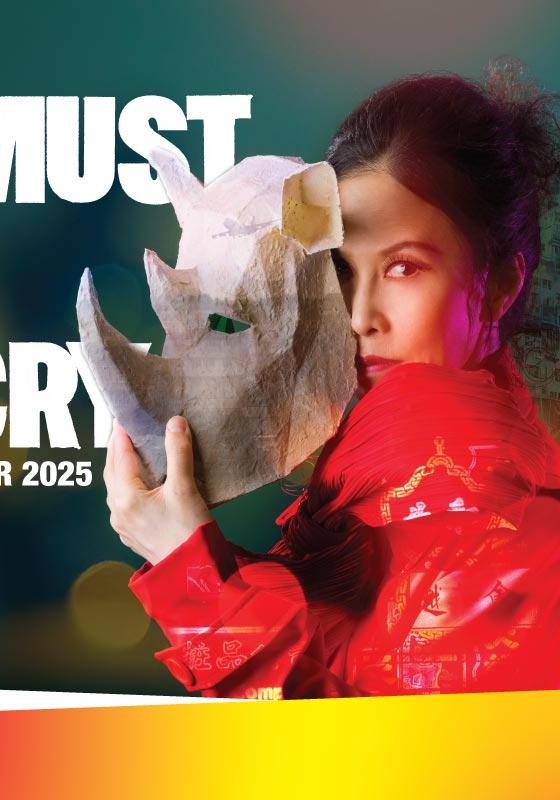 Performer in red holding a crafted papier mache rhino's head.
