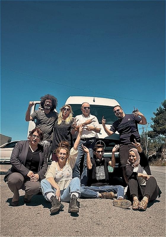 8 people posing in front of a white Mercedes van