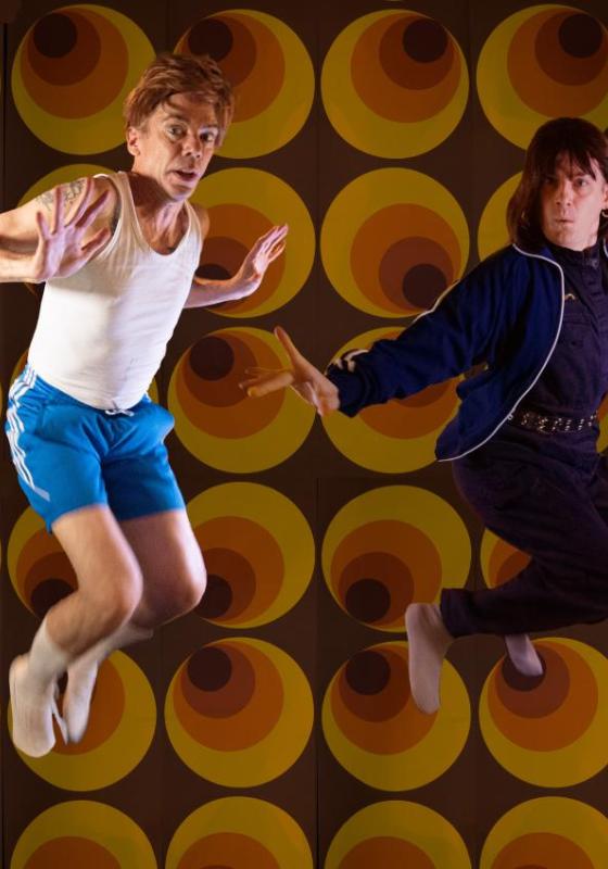 Two performers mid-air against a 70's style backdrop.