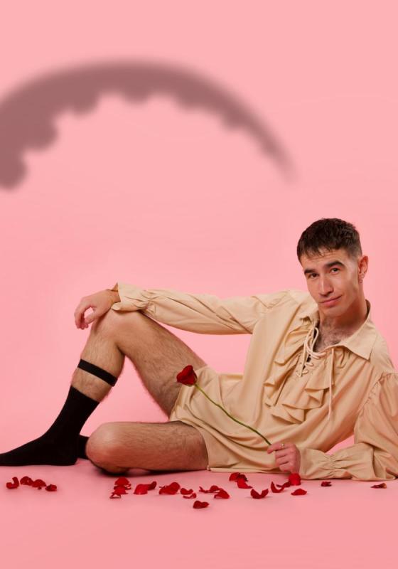The performer lying seductively with rose petals scattered on the floor and a shadow of a tentacle on the left hand side.