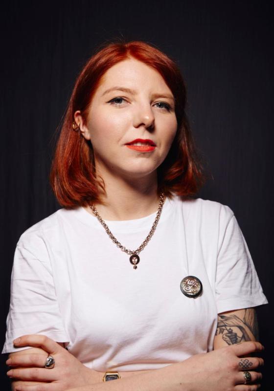 Marty looking at the camera with their arms crossed and wearing a white t-shirt.