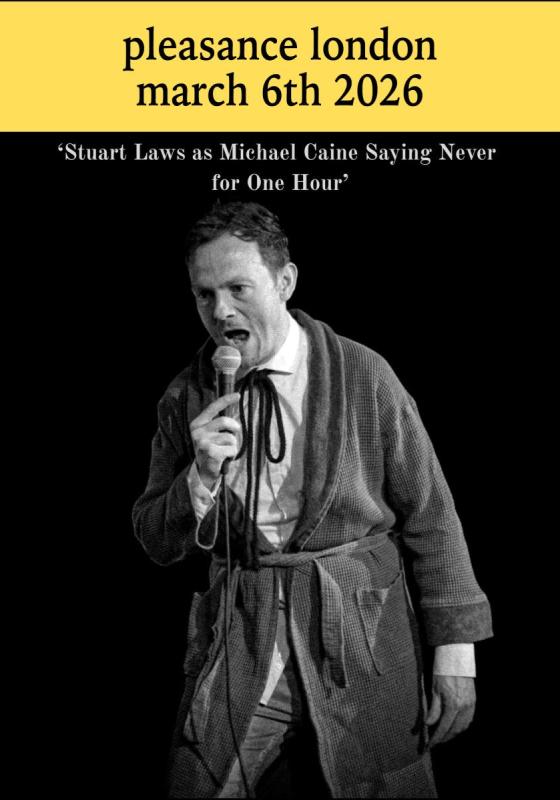 Stuart Laws in black and white wearing a dressing gown and holding a microphone.