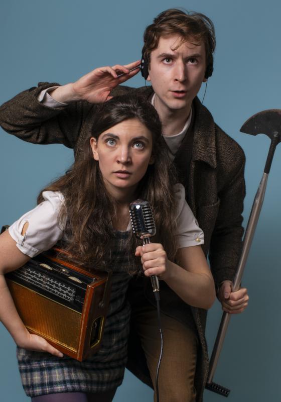 A man and a woman sleuths, one holds a microphone, the other a shovel. They look inquisitive. 
