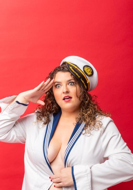 Mel McGlensey salutes whilst wearing a low-cut sailors uniform.