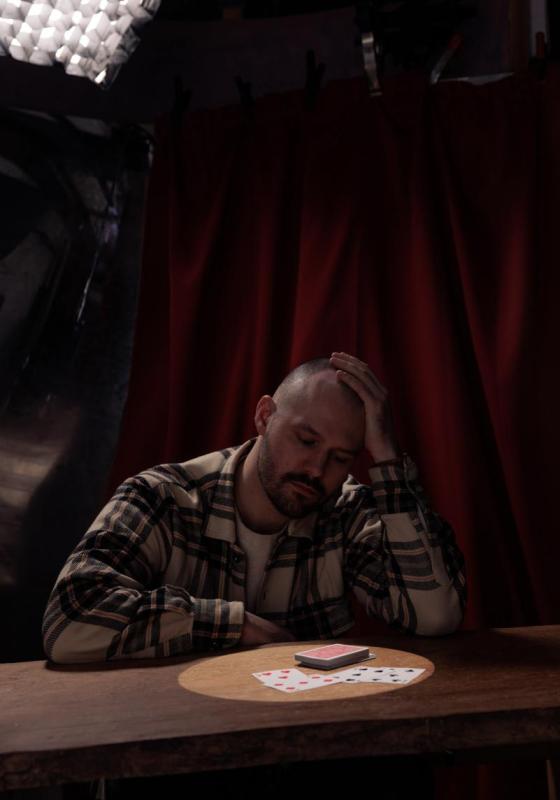 Andrew looks introspectively down at a table where a deck of cards is lit by a spotlight.