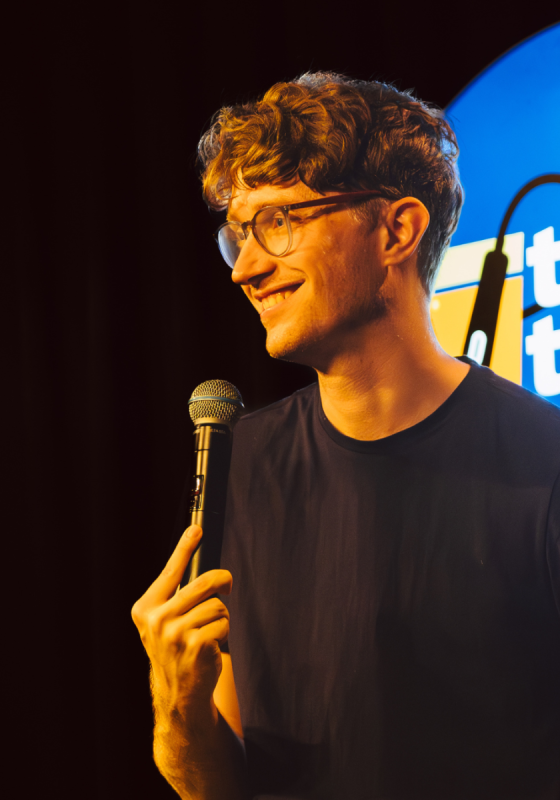 Photo of performer on stage holding a microphone.