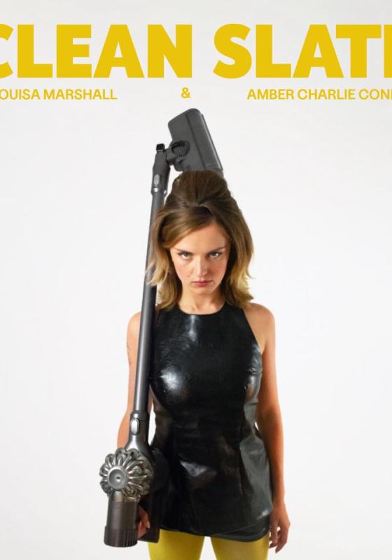 woman staring down the camera holding a hoover