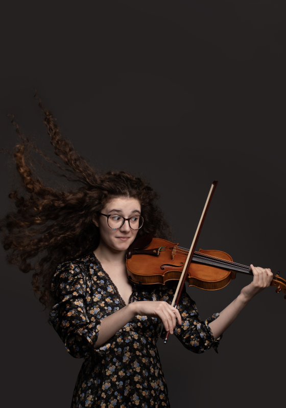 Photo of performer holding a violin, poised to play.