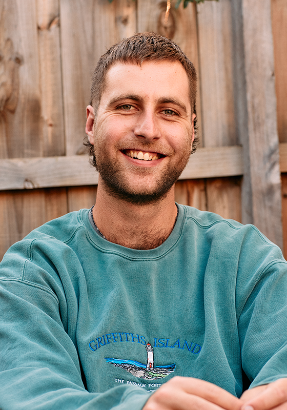 Picture of Lewis smiling in a blue sweatshirt.