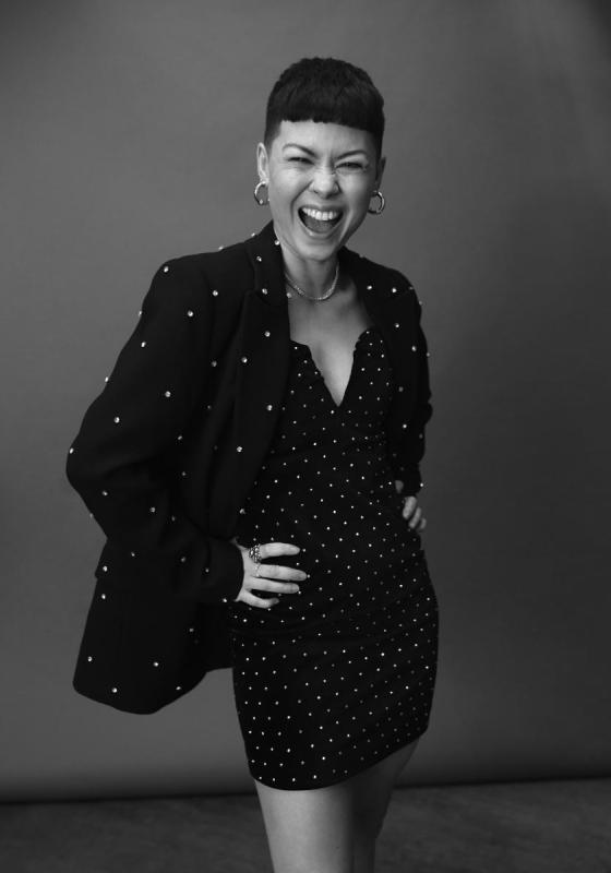 Black and white headshot of Anna wearing a dress full of sparkles and matching suit jacket.