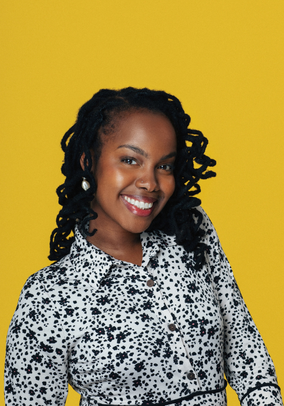 Sharon smiling brightly against a yellow backdrop.