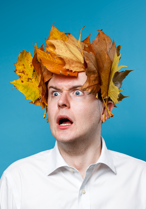 Photo of Andrew wearing a crown full of Autumn leaves looking startled.