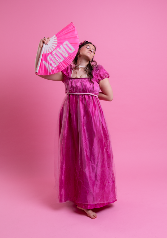 Photo of Clementine in pink period dress holding a fan with the text DADDY printed on it.